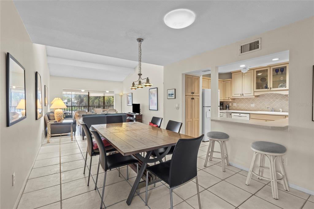 A dining area with a wooden table and chairs sits adjacent to an open kitchen — 1633 BOATHOUSE CIRCLE UNIT 232, SARASOTA, FL