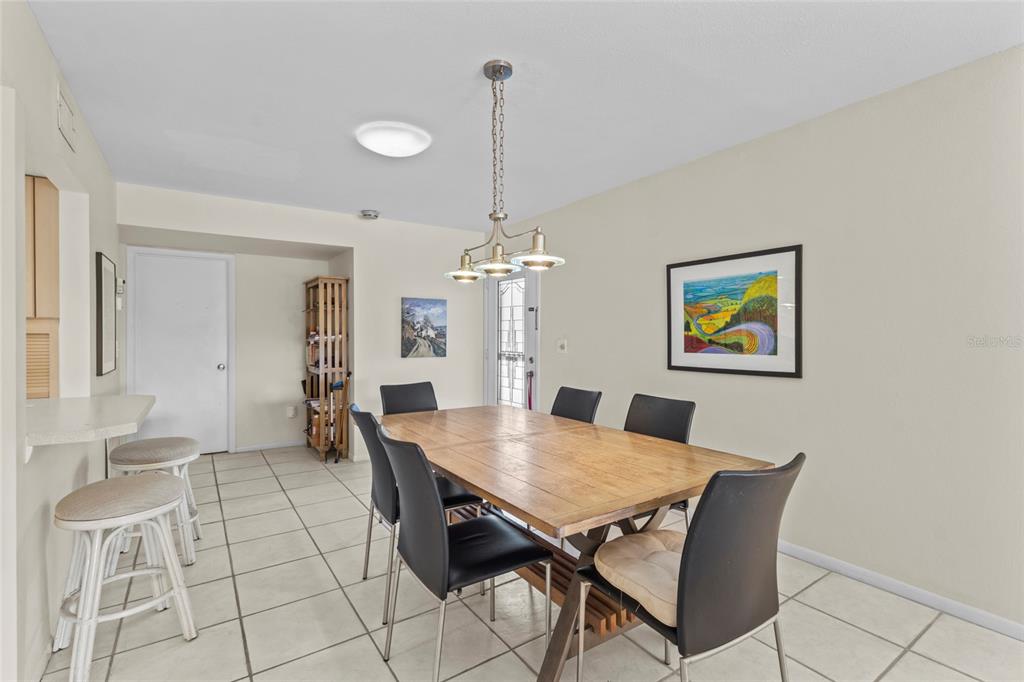 A dining room features a wooden table, black chairs, tile flooring, and a hanging light fixture — 1633 BOATHOUSE CIRCLE UNIT 232, SARASOTA, FL