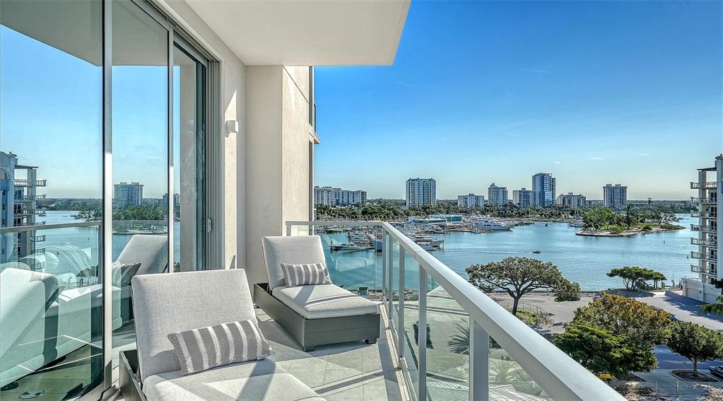 An aerial view shows waterfront high-rise apartment buildings with a swimming pool and nearby boats — 253 GOLDEN GATE POINT UNIT 701, SARASOTA, FL