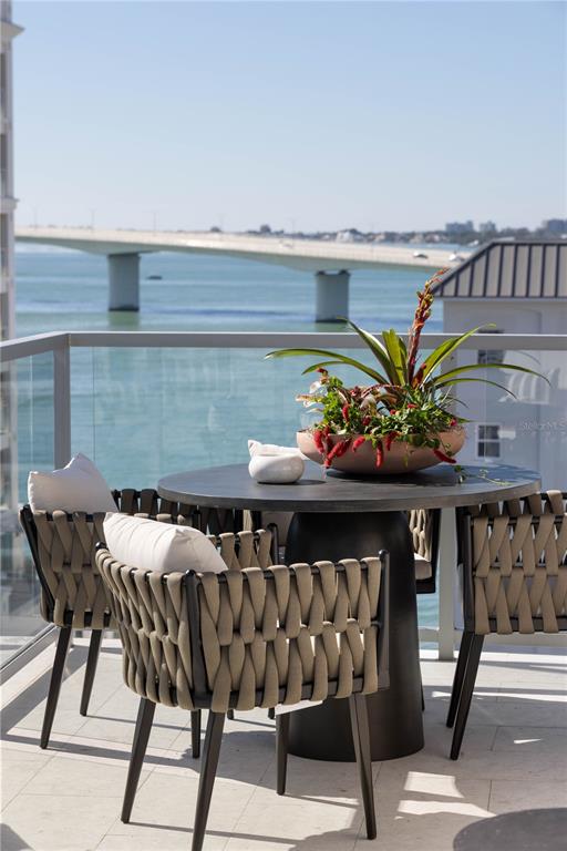 A balcony with two lounge chairs overlooks a harbor and a city skyline — 253 GOLDEN GATE POINT UNIT 701, SARASOTA, FL