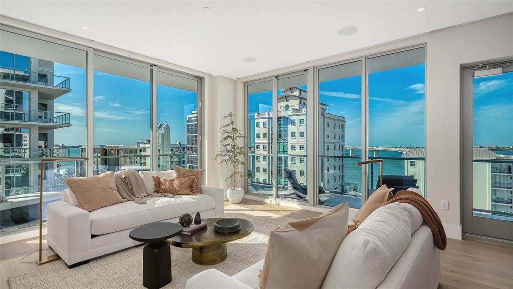 A balcony with a round table and woven chairs overlooks a bridge and the ocean — 253 GOLDEN GATE POINT UNIT 701, SARASOTA, FL