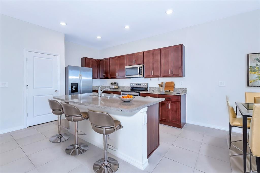 A modern kitchen features dark wood cabinets, granite countertops, a center island, and stainless appliances — 8657 MILESTONE DRIVE, SARASOTA, FL