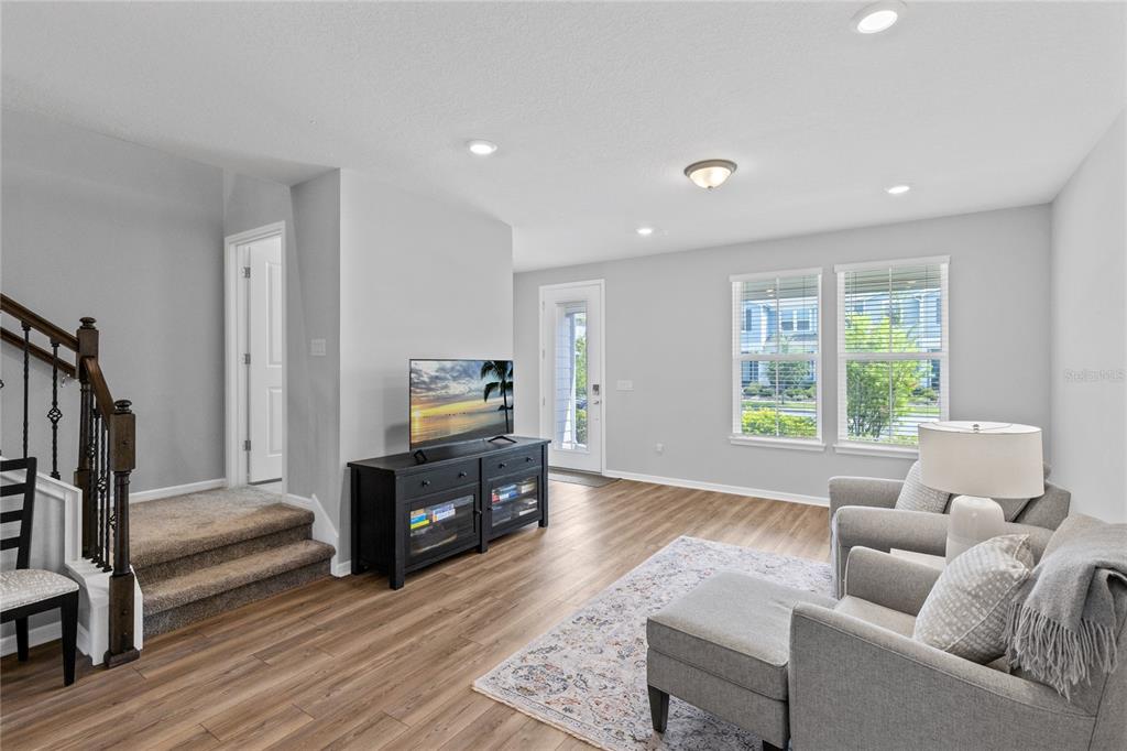 A living room with wood-look flooring, a staircase, a television console, and two armchairs — 14376 SAPELO BEACH DRIVE, ORLANDO, FL