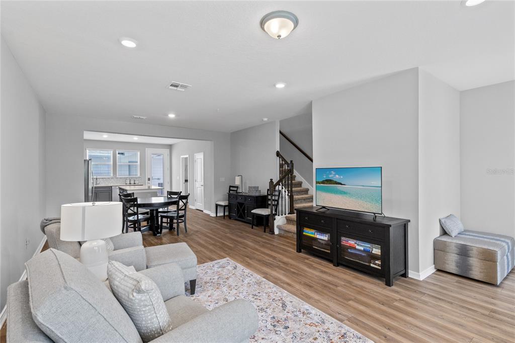 An open-concept living room and dining area featuring wood-look flooring and a staircase — 14376 SAPELO BEACH DRIVE, ORLANDO, FL
