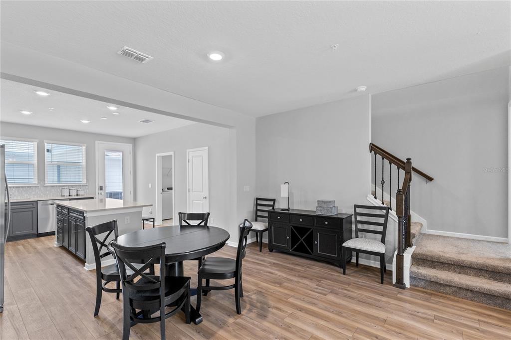 A dining area with a round table, chairs, and a staircase next to a kitchen — 14376 SAPELO BEACH DRIVE, ORLANDO, FL