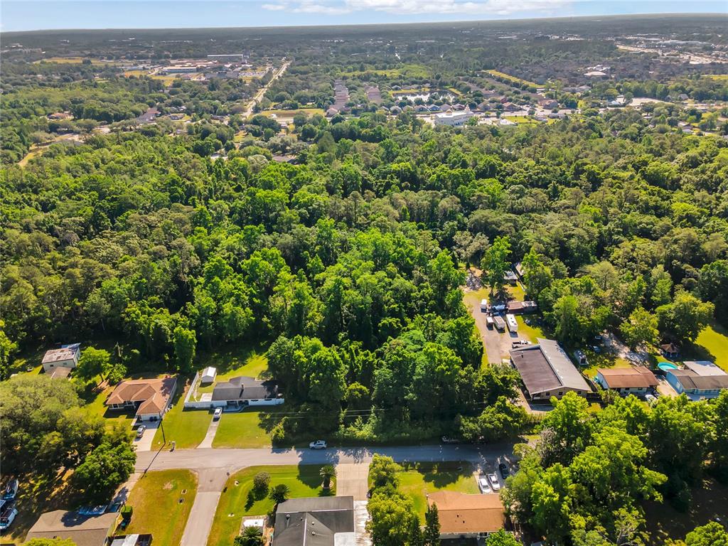 An aerial view shows a residential neighborhood with houses surrounded by dense green trees — 2209 GRAYSON DRIVE, ORLANDO, FL