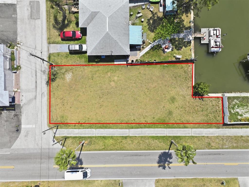 An aerial view shows a vacant, rectangular waterfront lot outlined in red — 13939 MURIEL DRIVE, HUDSON, FL