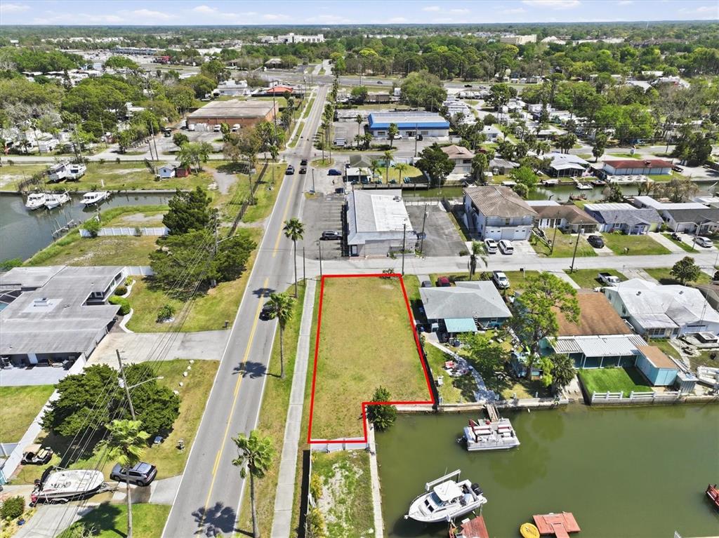 An aerial view shows a vacant, rectangular waterfront lot outlined in red next to a road — 13939 MURIEL DRIVE, HUDSON, FL