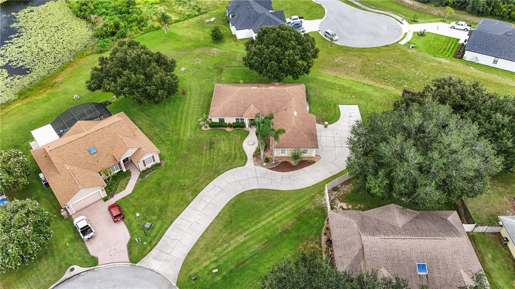 An aerial view shows three houses with brown roofs, large lawns, and concrete driveways — 11546 NICE COURT, CLERMONT, FL