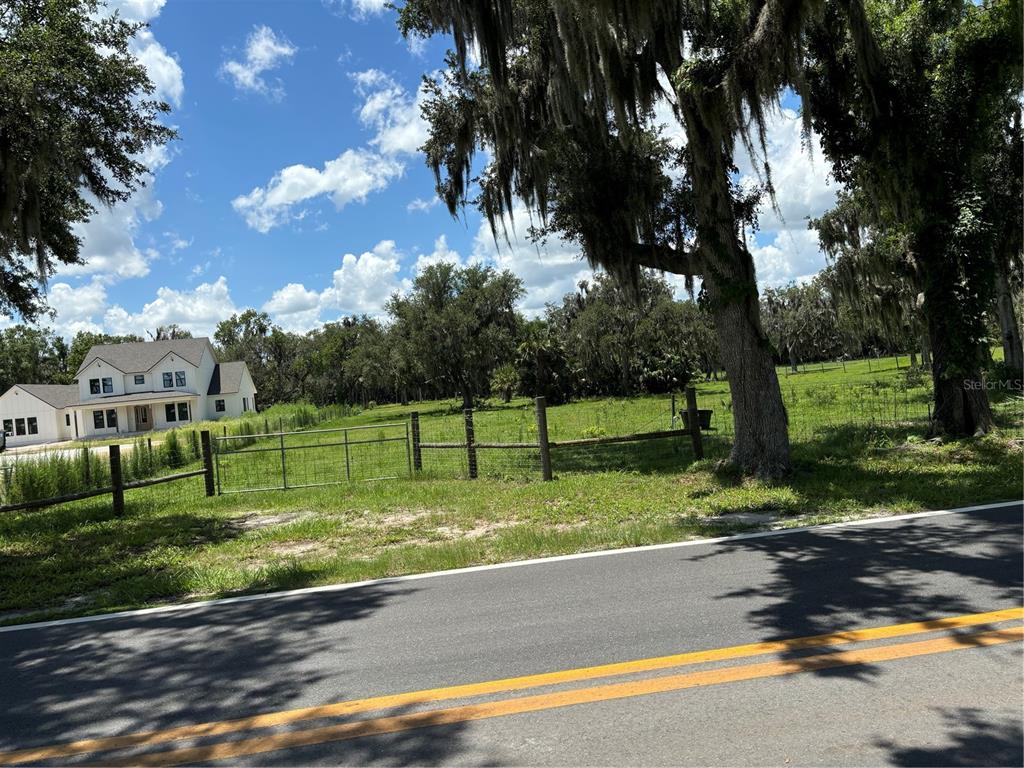 A view of a grassy lot with a fence and a house in the background — PINE WAY Lot 4E, SANFORD, FL