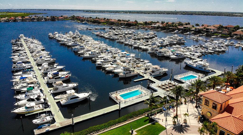 A large motor yacht is docked at a concrete marina pier under a clear sky — 102 RIVIERA DUNES WAY UNIT C10, PALMETTO, FL