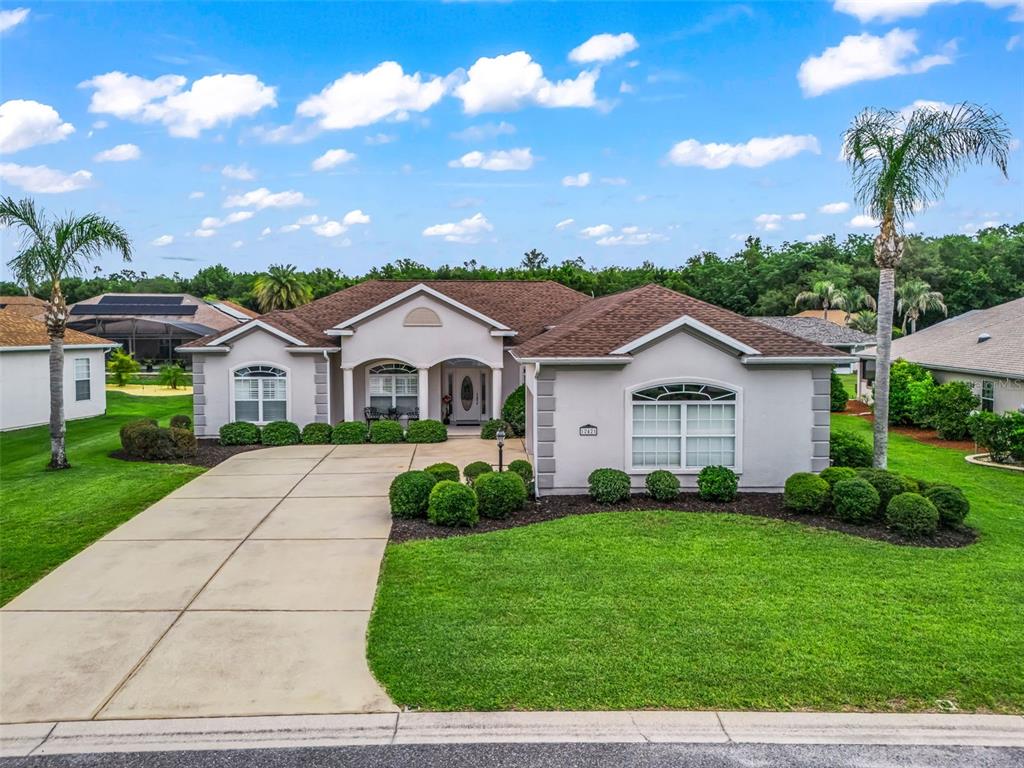 A single-story suburban house with a concrete driveway, manicured lawn, and palm trees — 12421 SE 174TH LOOP, SUMMERFIELD, FL