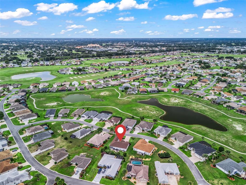An aerial view shows a residential neighborhood with houses surrounding a golf course and ponds — 12421 SE 174TH LOOP, SUMMERFIELD, FL