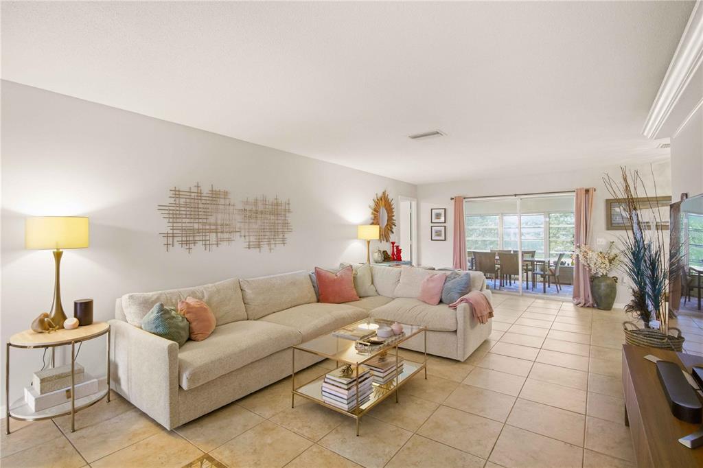 A living room features a large sectional sofa, a glass coffee table, and tile flooring — 7354 W COUNTRY CLUB DRIVE N, SARASOTA, FL