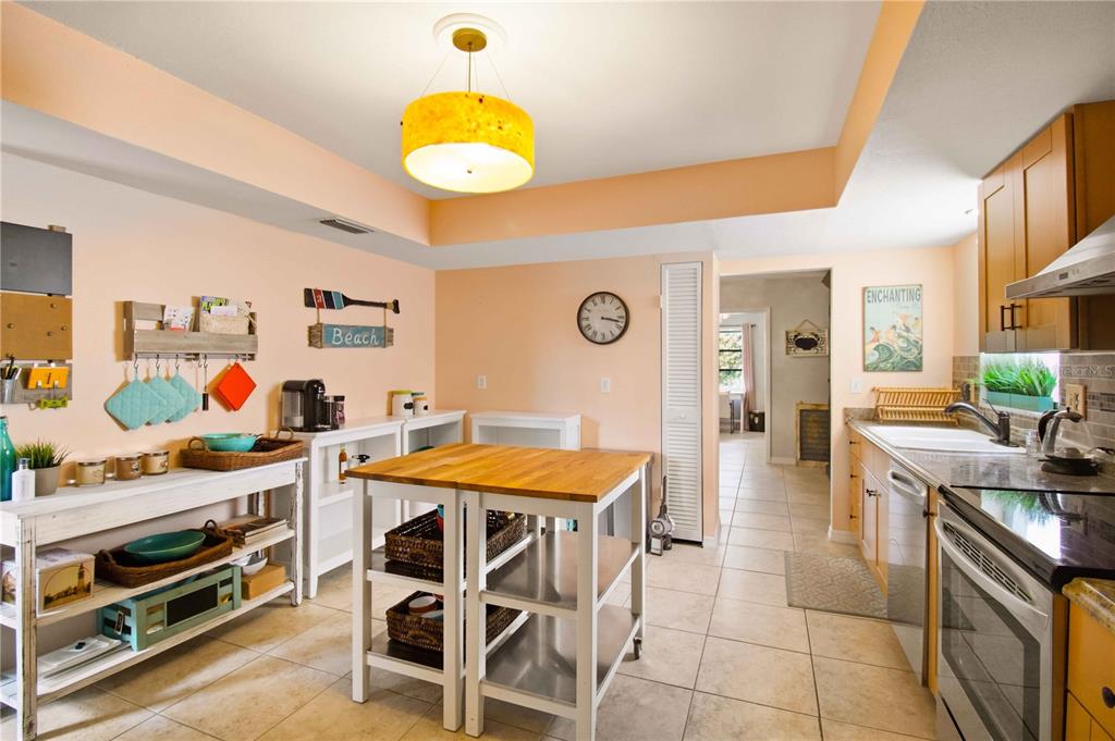 A kitchen features a wooden island, light-colored walls, tile flooring, and wooden cabinetry — 7354 W COUNTRY CLUB DRIVE N, SARASOTA, FL