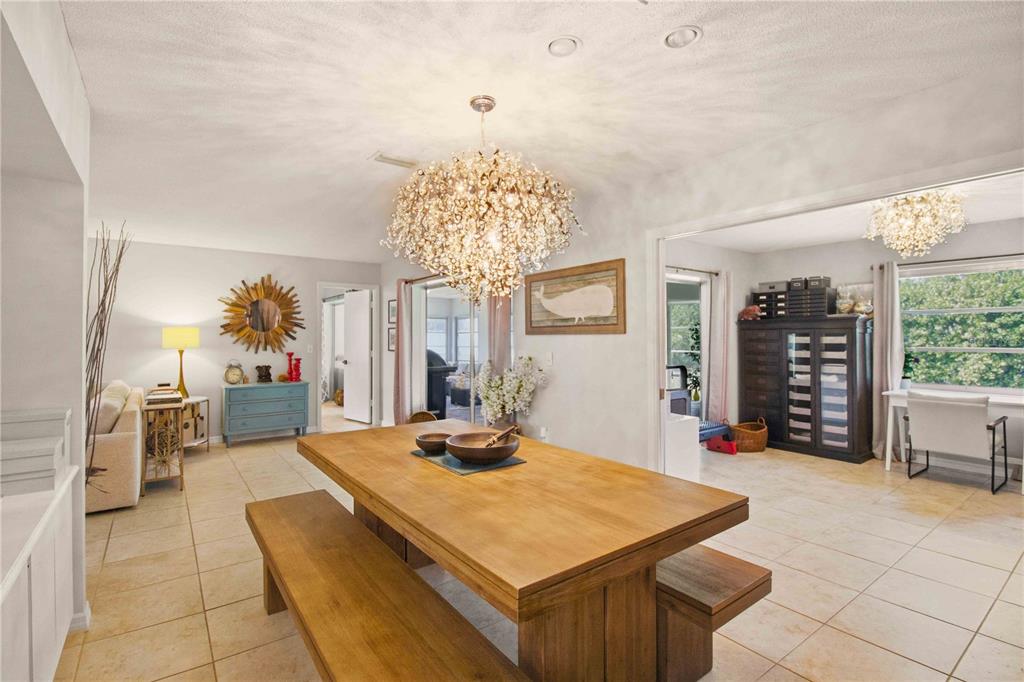 A dining room features a large wooden table, benches, and a prominent crystal chandelier — 7354 W COUNTRY CLUB DRIVE N, SARASOTA, FL