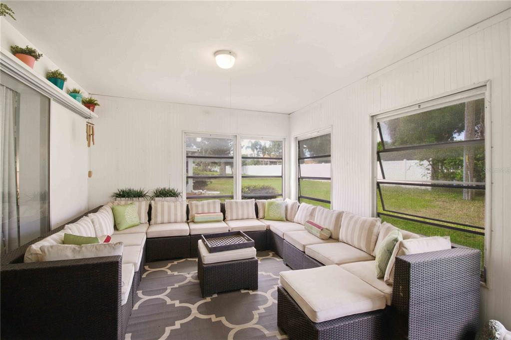 A sunroom features a large U-shaped wicker sectional sofa on a patterned area rug — 7354 W COUNTRY CLUB DRIVE N, SARASOTA, FL