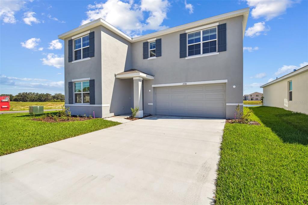 A two-story suburban house with a gray stucco exterior and an attached two-car garage — 2774 COMMON FIG RUN, WESLEY CHAPEL, FL