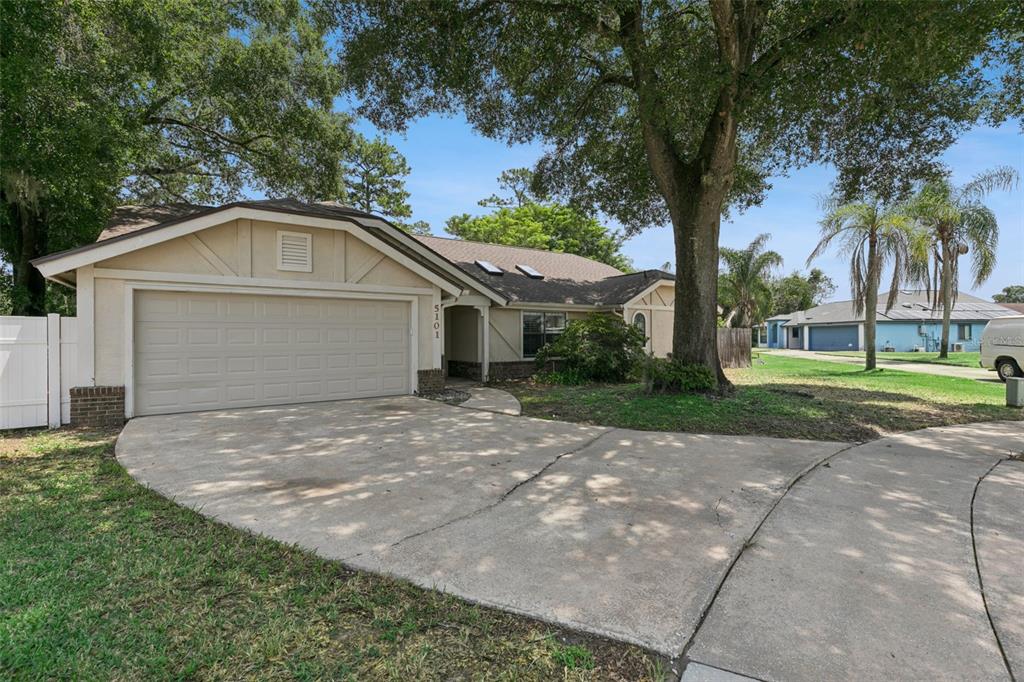 A single-story house with a beige exterior, a two-car garage, and a large front tree — 5101 GOLDENWOOD DRIVE, ORLANDO, FL