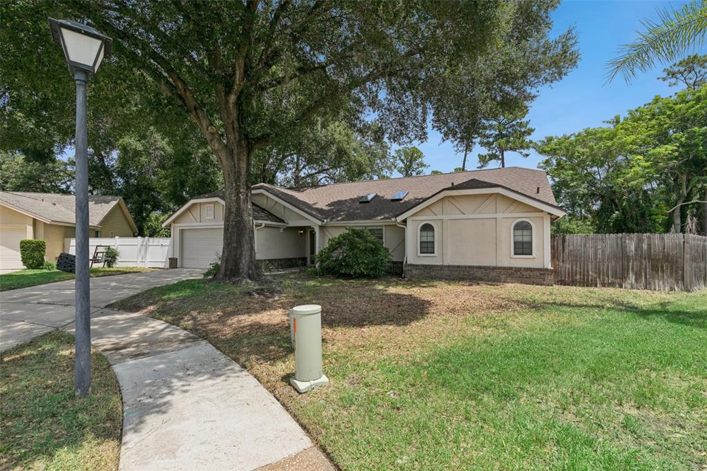 A single-story house with a beige exterior, a two-car garage, and a large front tree — 5101 GOLDENWOOD DRIVE, ORLANDO, FL