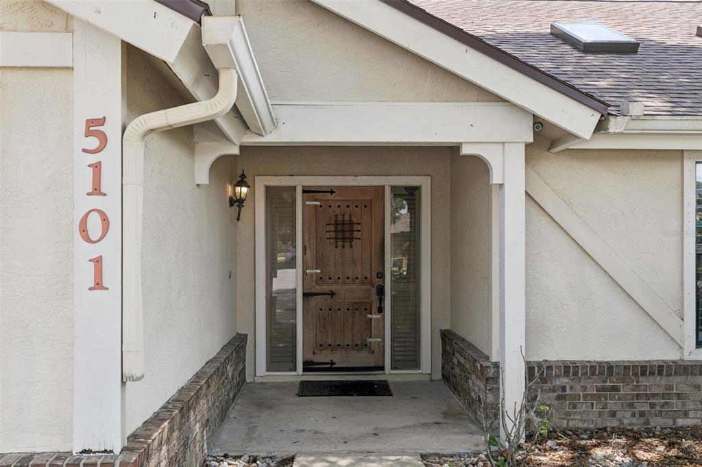 The front entrance of a house features a wooden door with a metal grate — 5101 GOLDENWOOD DRIVE, ORLANDO, FL