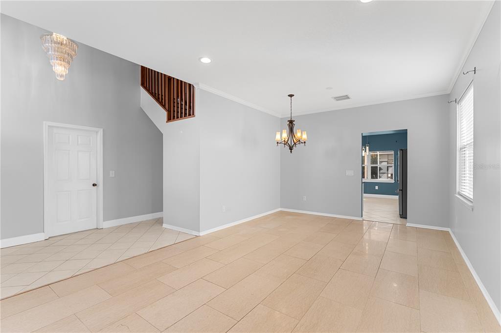 A spacious dining room features light tile flooring, gray walls, and a decorative chandelier — 27416 BREAKERS DRIVE, WESLEY CHAPEL, FL