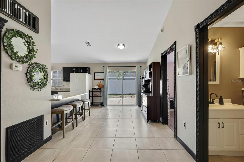 A living room features a blue front door, a gray sectional sofa, and a wall-mounted television — 7484 SUSQUEHANNA TRAIL, SPRING HILL, FL