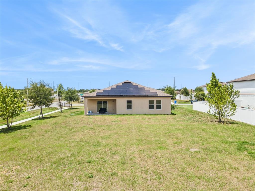 The rear exterior of a single-story house features a solar panel array on the roof — 903 SHIMMERING OAKS LANE, SEFFNER, FL