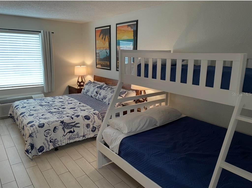 A bedroom features a queen bed with patterned bedding and a white wooden bunk bed — 7150 N TAMIAMI TRAIL UNIT N420, SARASOTA, FL