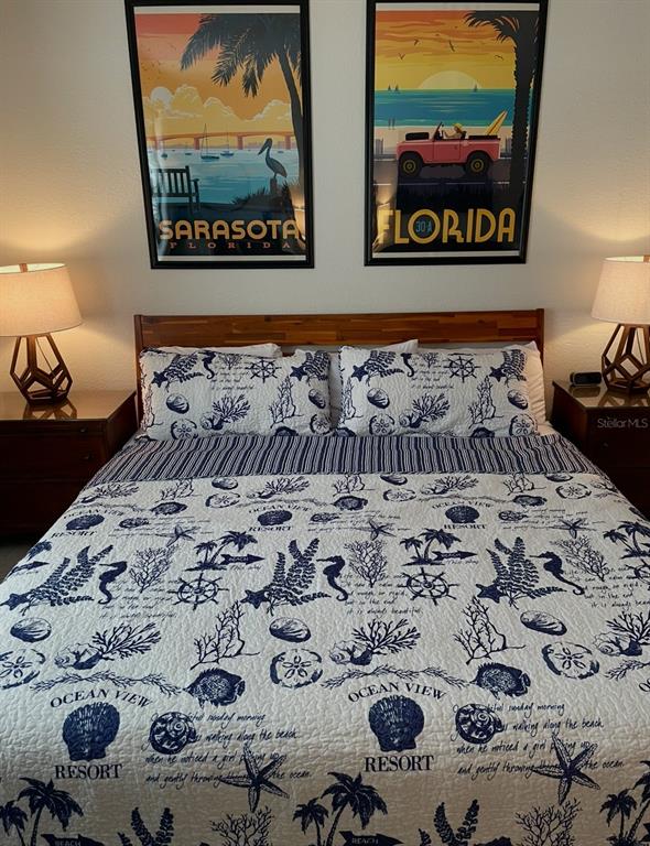 A bedroom features a bed with a nautical-themed quilt, two nightstands, and two framed posters — 7150 N TAMIAMI TRAIL UNIT N420, SARASOTA, FL