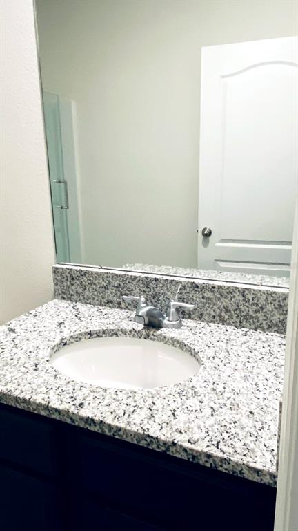 A bathroom vanity features a granite countertop, an oval sink, and a large wall mirror — 1128 FOX PATH ROAD, DAVENPORT, FL