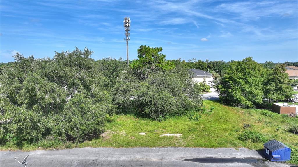 An elevated view of a vacant, grassy lot featuring mature trees and a cell tower — 0 PLAZA DRIVE NW, KISSIMMEE, FL