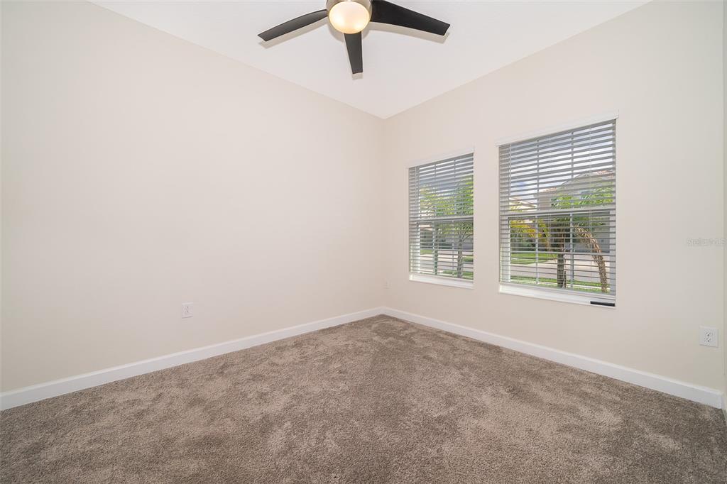 An empty bedroom features beige walls, gray carpeting, a ceiling fan, and two windows — 1173 TRAPPERS TRAIL LOOP, CHAMPIONS GATE, FL