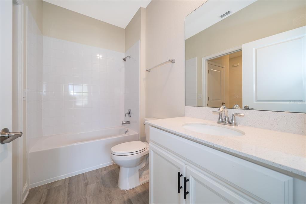 A bathroom features a white vanity, a toilet, and a shower-tub combination with white tiles — 1173 TRAPPERS TRAIL LOOP, CHAMPIONS GATE, FL