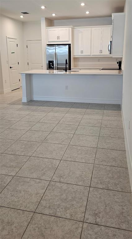 A kitchen features white cabinets, stainless steel appliances, and a breakfast bar over tiled flooring — 180 RAINWOOD STREET, GROVELAND, FL