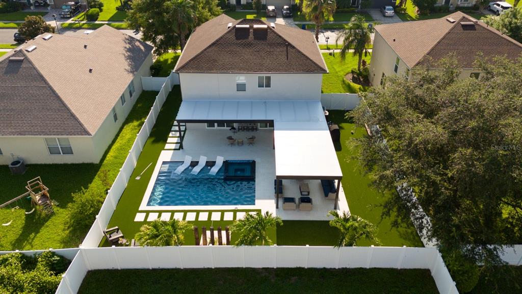 An aerial view shows a house with a backyard pool, covered patio, and white fencing — 526 FIRST CAPE CORAL DRIVE, WINTER GARDEN, FL