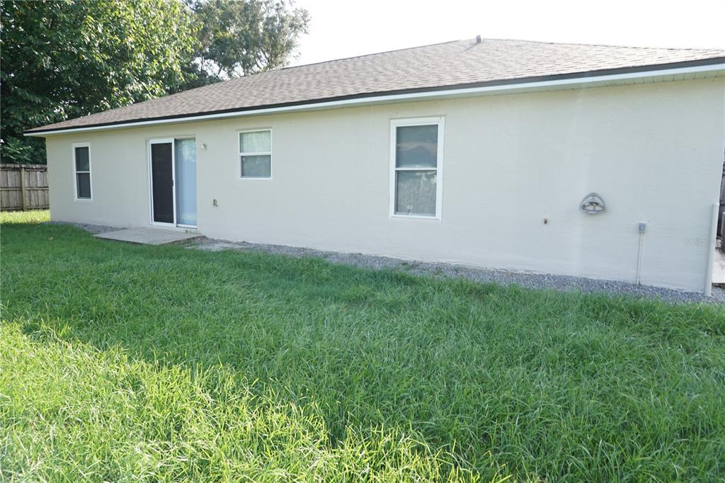 The exterior of a beige house features a sliding glass door and several windows — 6655 NW 15TH AVENUE, OCALA, FL