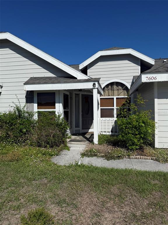 The exterior of a light gray, single-story house features a covered entryway and arched window — 7606 37TH STREET CIRCLE E, SARASOTA, FL