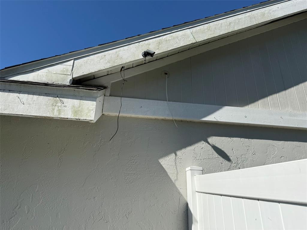 An exterior view of a house corner showing a security camera and loose electrical wires — 7606 37TH STREET CIRCLE E, SARASOTA, FL