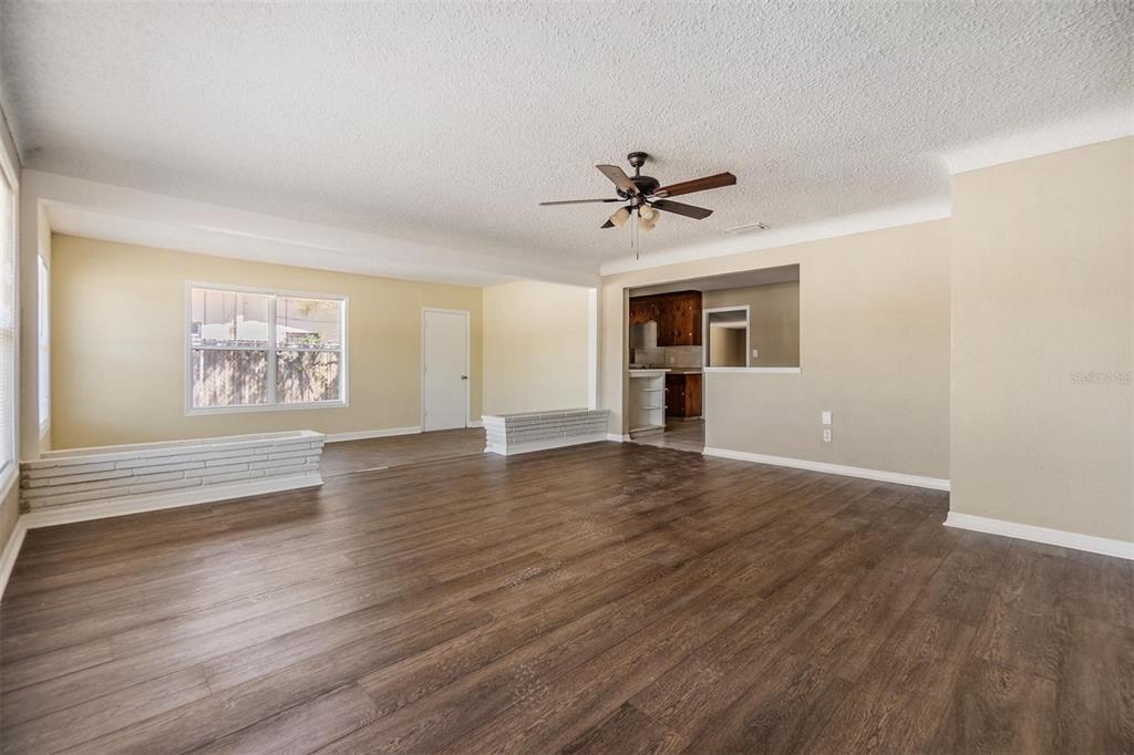 A spacious living room features wood-look flooring, a ceiling fan, and white brick planter boxes — 5130 DR MARTIN LUTHER KING JR ST S, ST PETERSBURG, FL