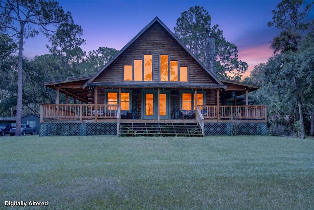 A wooden cabin with a large front porch and a gabled roof at twilight — 5365 PACES LANDING ROAD, MIMS, FL