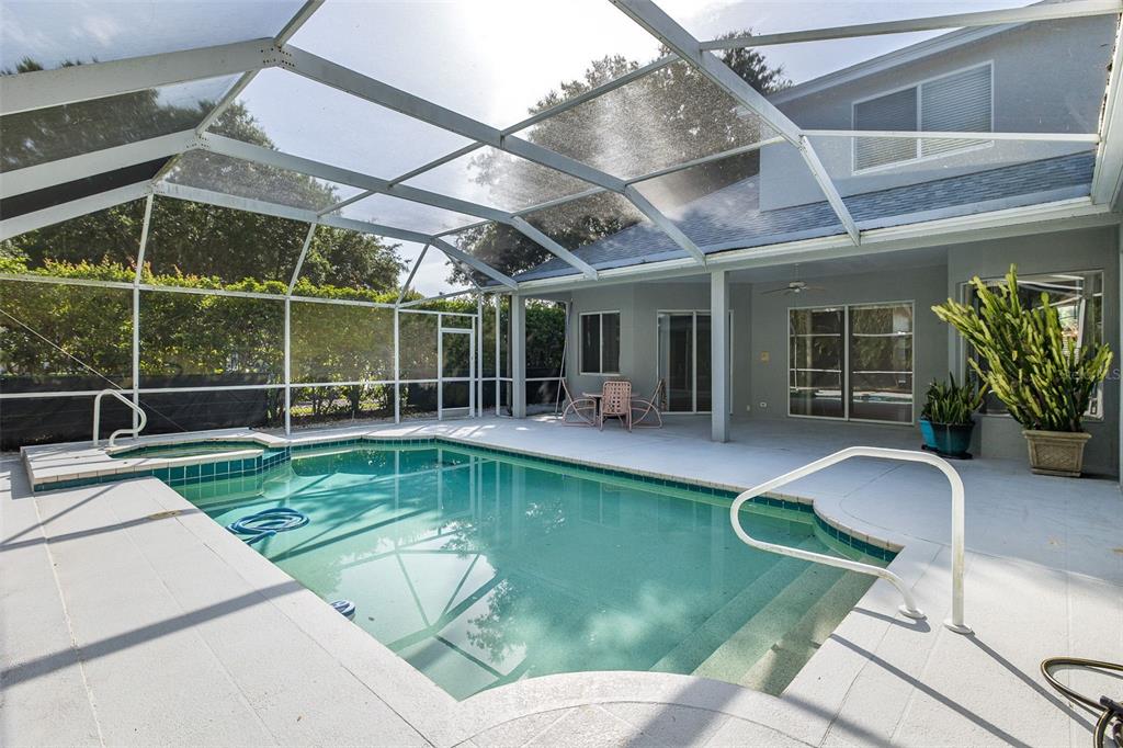 A screened-in patio features a swimming pool with a spa and a concrete deck — 2151 EDELWEISS LOOP, TRINITY, FL