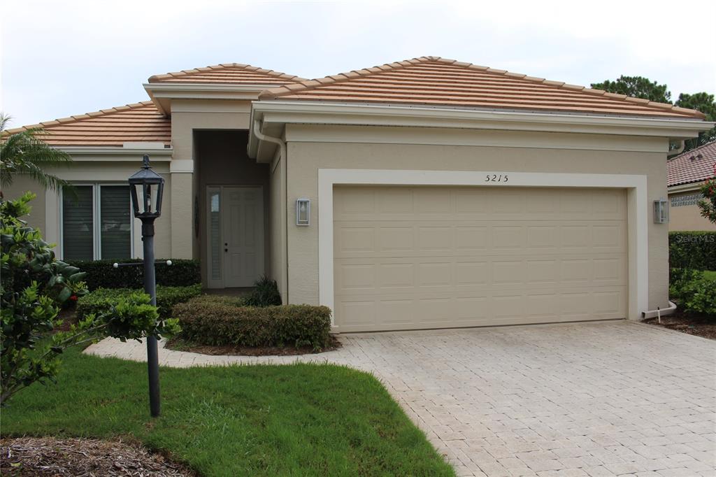 A single-story house features a tan stucco exterior, a tiled roof, and a two-car garage — 5215 97TH STREET E, BRADENTON, FL