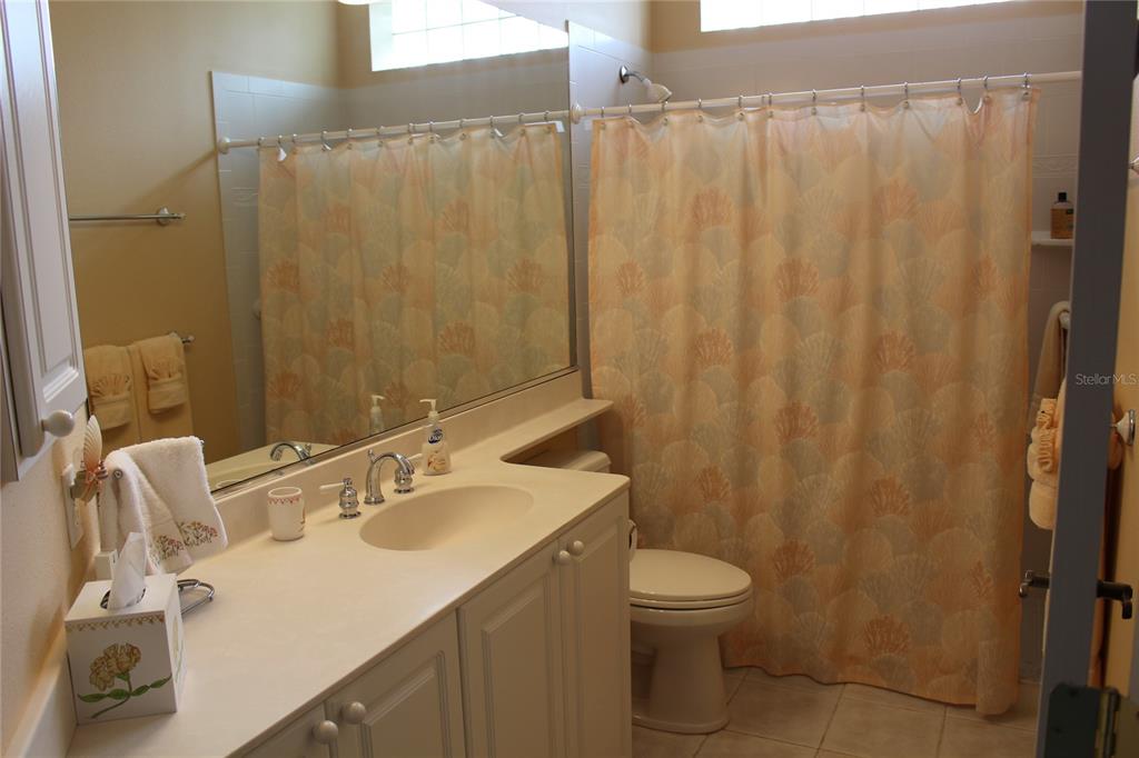 A bathroom features a white vanity, a large mirror, and a shower with a patterned curtain — 5215 97TH STREET E, BRADENTON, FL