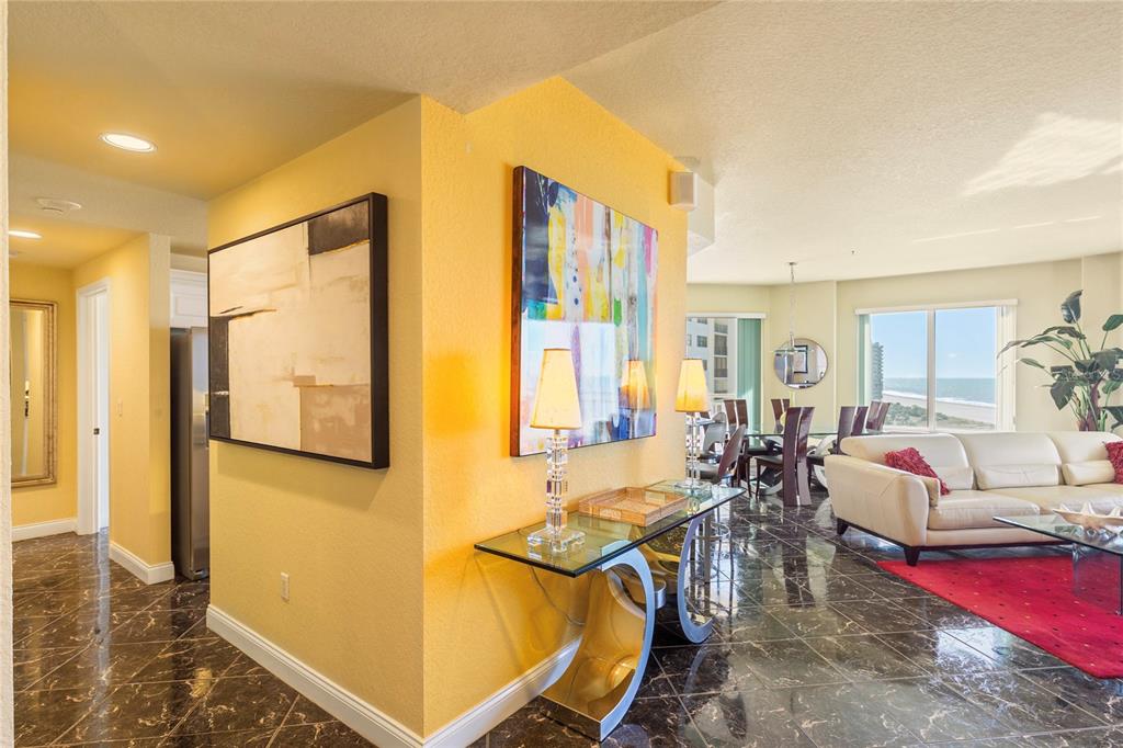 A living and dining area features yellow walls, dark marble floors, and ocean views — 1200 GULF BOULEVARD UNIT 1002, CLEARWATER, FL
