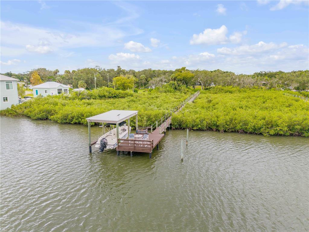 An aerial view shows a boat docked at a wooden pier extending into the water — 4697 BAYFIELD HARBOR LANE, EDGEWATER, FL