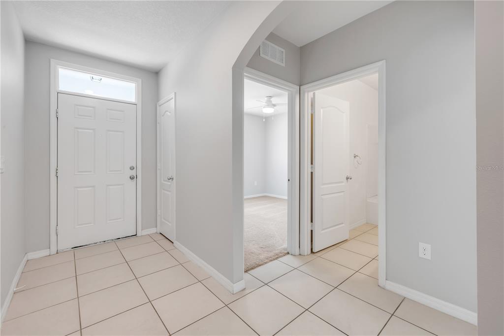 A bright entryway features tile flooring, a white front door, and a console table — 4697 BAYFIELD HARBOR LANE, EDGEWATER, FL