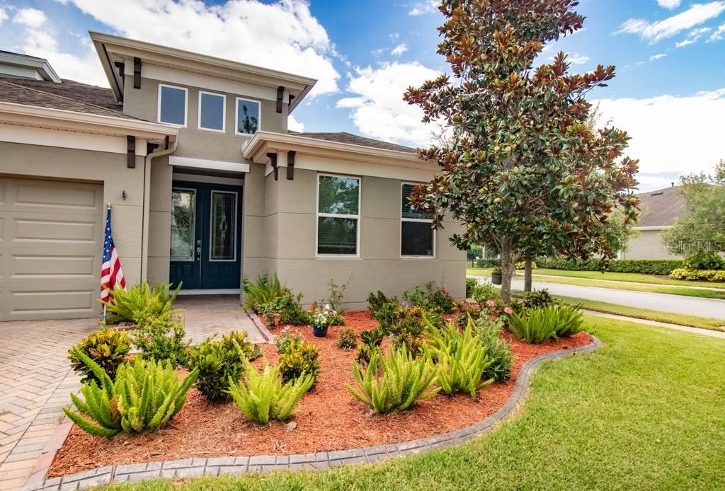 The exterior of a single-story house features a paved driveway, landscaping, and a front entrance — 16485 COURTYARD LOOP, LAND O LAKES, FL
