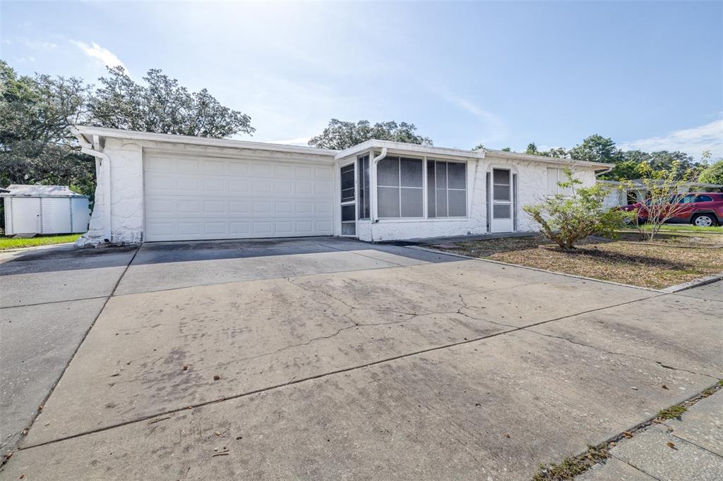 A white single-story house features a concrete driveway, a garage, and a screened-in porch — 4636 ACKERMAN STREET, NEW PORT RICHEY, FL