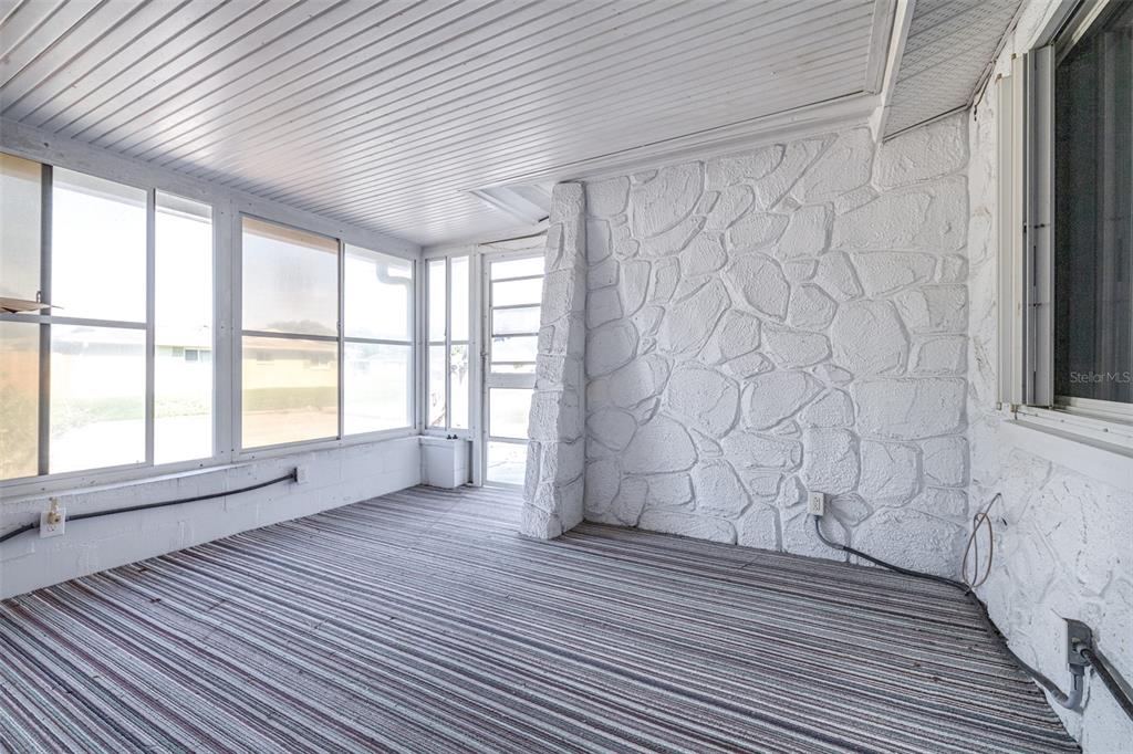 A sunroom features white painted stone walls, striped carpeting, and large windows — 4636 ACKERMAN STREET, NEW PORT RICHEY, FL